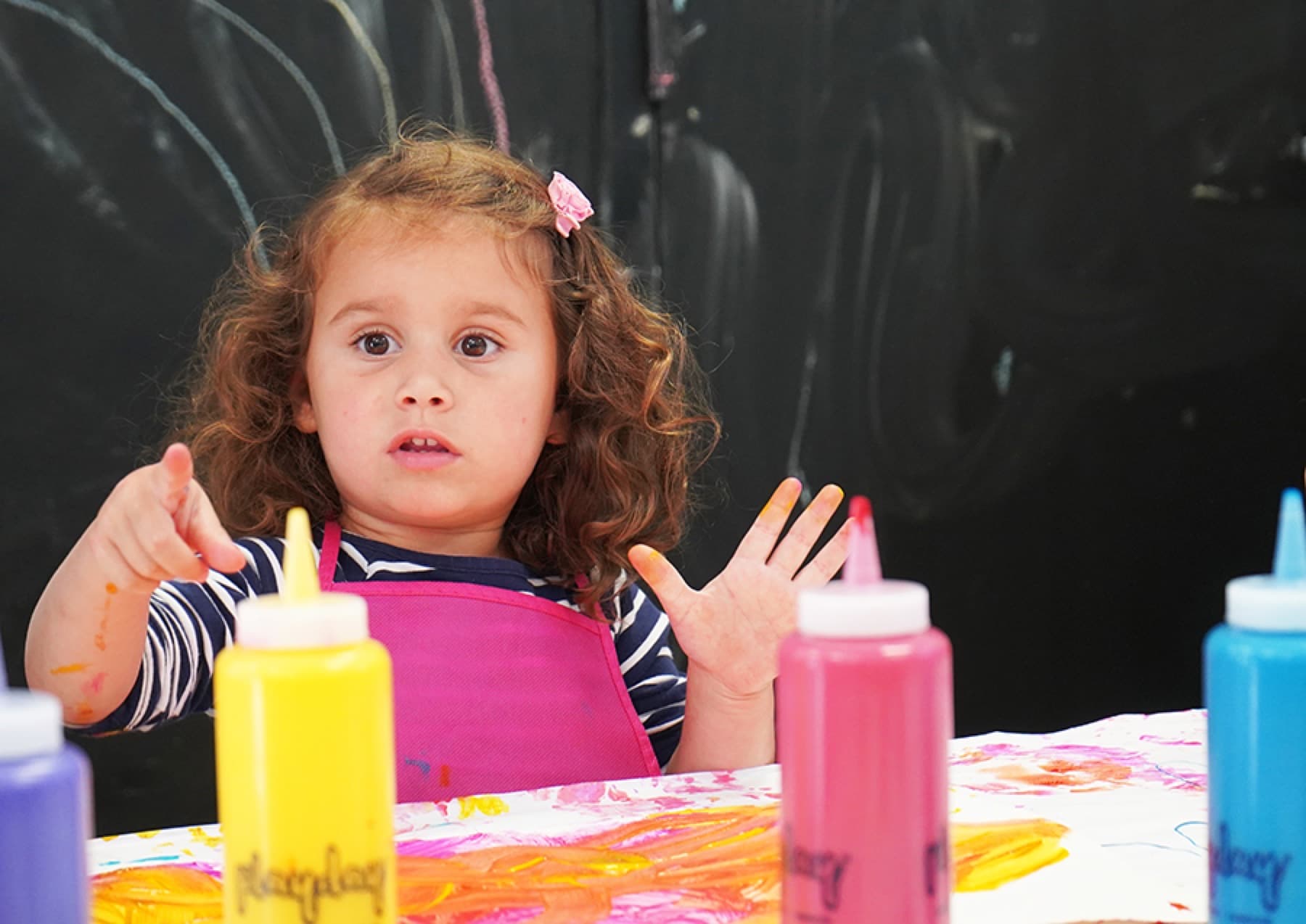 A toddler painting with PLAYDAY paints
