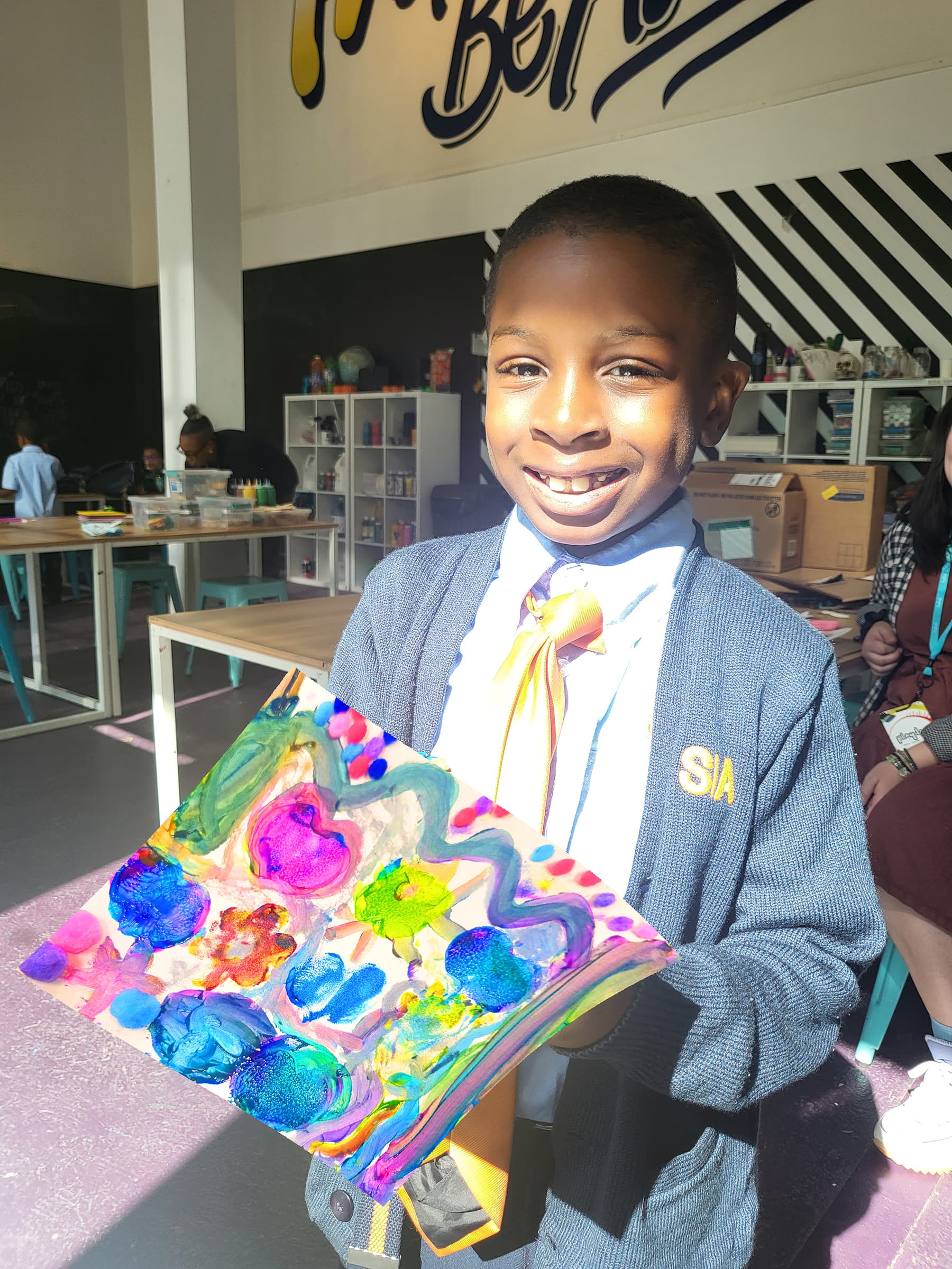 Child proudly holding their PLAYDAY artwork